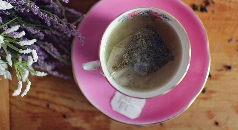 Tasse Tee neben der ein Strauß Lavendel liegt