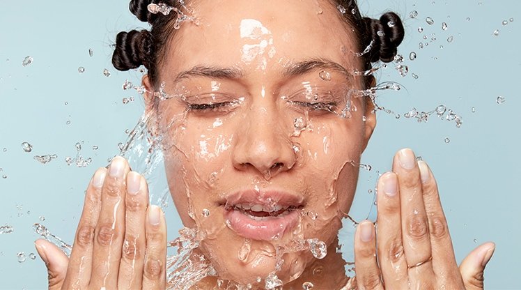 Frau wirft sich Wasser mit ihren Händen ins Gesicht