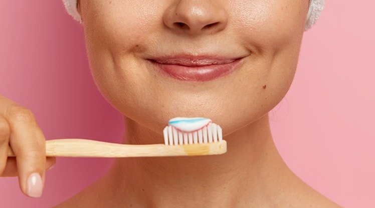 Eine junge Frau hält eine Zahnbürste mit Zahnpasta vor ihrem Gesicht