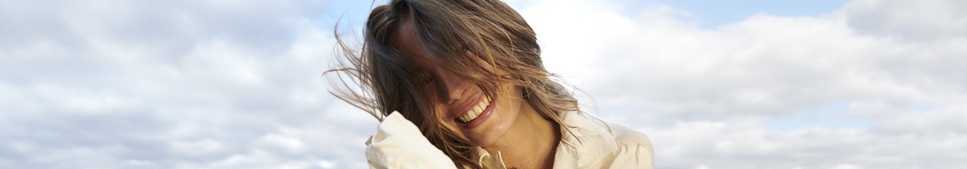 Eine lächelnde junge Frau wehen die Haare vor ihr Gesicht