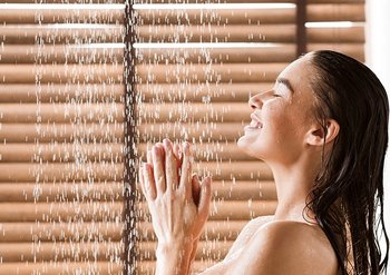 Eine Frau steht laechelnd unter der Dusche