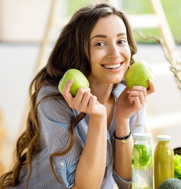 Frau hält Äpfel neben ihr Gesicht
