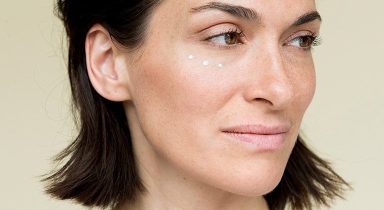 Frau mit aufgetragener Augencreme