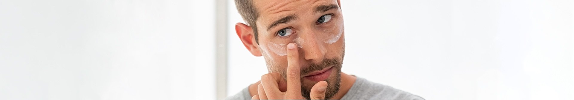 Mann trägt Creme auf die Augenpartie auf