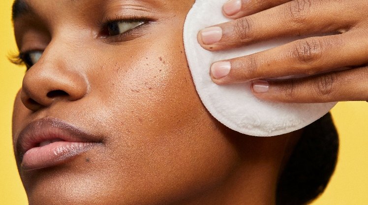 Junge Frau reinigt ihr Gesicht mit einem wiederverwendbaren Wattepad