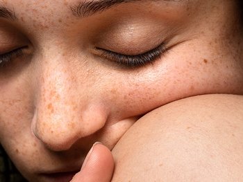 Gesicht einer Frau mit Sommersprossen, die sich an ihrer Schulter festhält