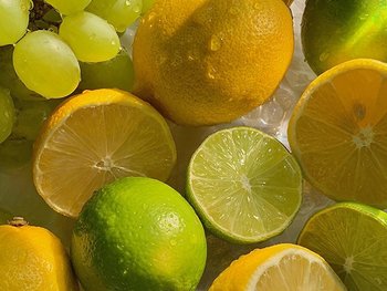 Zitronen, Limetten und Trauben liegen nebeneinander auf einem Tablett