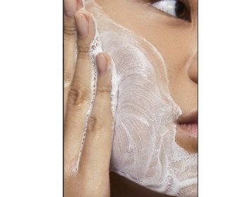 Frau wendet Double Cleansing an und wäscht ihr Gesicht mit einem schäumenden Cleanser
