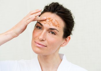 Frau trägt Creme auf ihrer Stirn auf