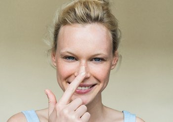 Frau berührt lachend ihre Nase