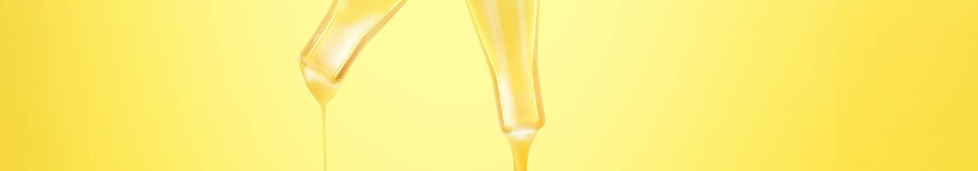 Zwei Pipetten eines Gesichtsserums vor strahlend gelbem Hintergrund