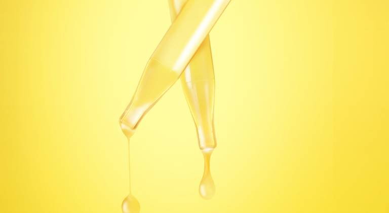 Zwei Pipetten eines Gesichtsserums vor strahlend gelbem Hintergrund