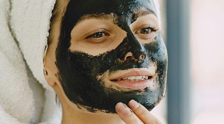 Frau trägt Peeling auf ihre Nase auf