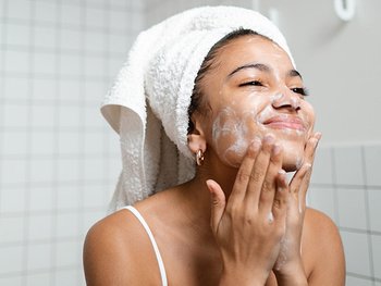 Eine junge Frau seift sich ihr gesicht ein