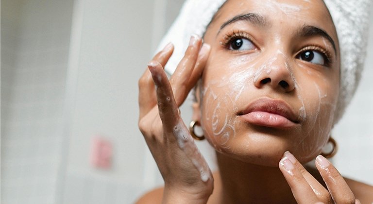 Frau beim Auftragen einer Gesichtsmaske gegen Pickel