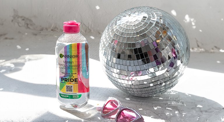 Mizellenwasser Pride Edition steht neben einer Discokugel und einer rosa Sonnenbrille