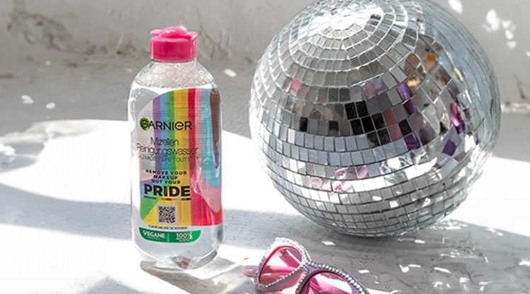 Mizellenwasser Pride Edition steht neben einer Discokugel und einer rosa Sonnenbrille