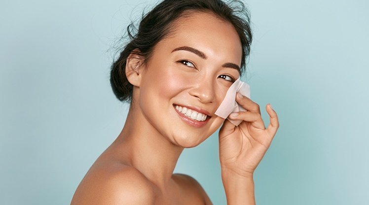 Junge Frau reinigt sich mit einem Reinigungs-Pad ihr Gesicht