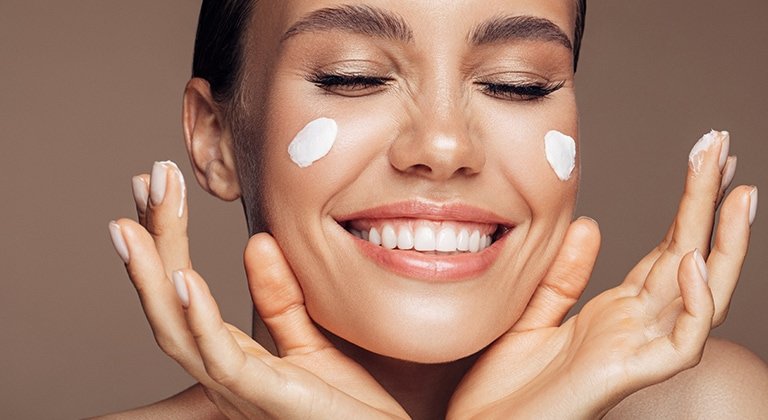 Frau mit Gesichtscreme auf den Wangen lächelt