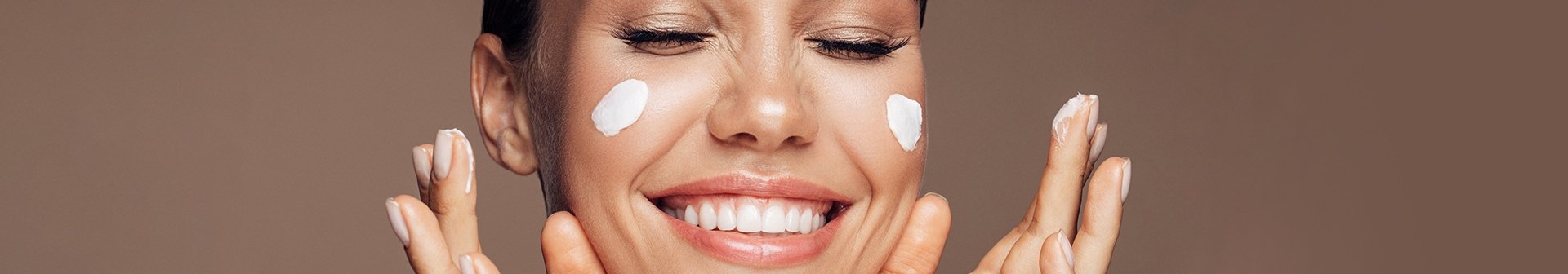 Frau mit Gesichtscreme auf den Wangen lächelt