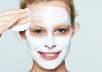 Eine Frau wäscht ihre Peeling-Maske vom Gesicht ab