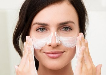 Eine Frau trägt ein Peeling auf ihre Wangen auf