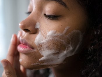 Eine junge Frau seift ihre Wangen ein