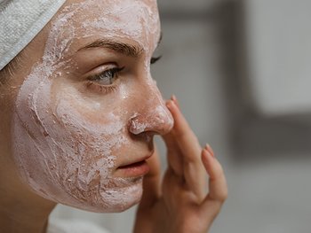 Eine junge Frau mit Gesichtsmaske und einem Tuch um ihre Haare