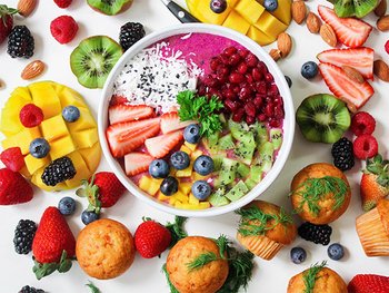 verschiedene Obstsorten z.T. aufgeschnitten & drapiert auf einer weißen Fläche