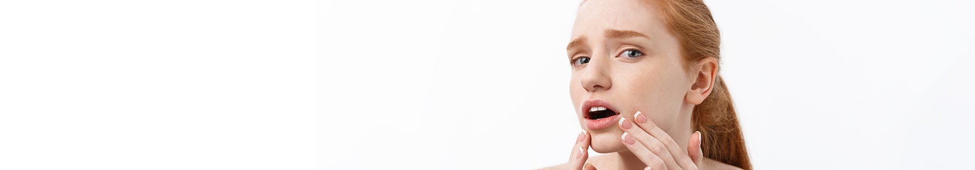 Eine junge Frau schaut erschrocken und fasst sich mit beiden Händen an ihren Kinnbereich