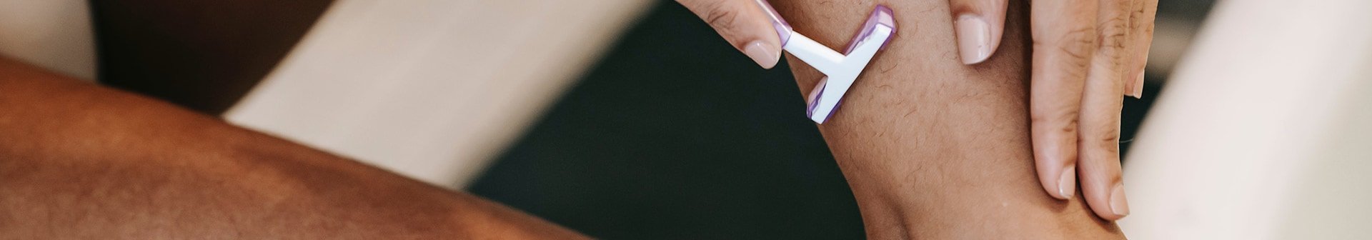 Eine Frau rasiert sich die Wade mit einer Einwegrasierer