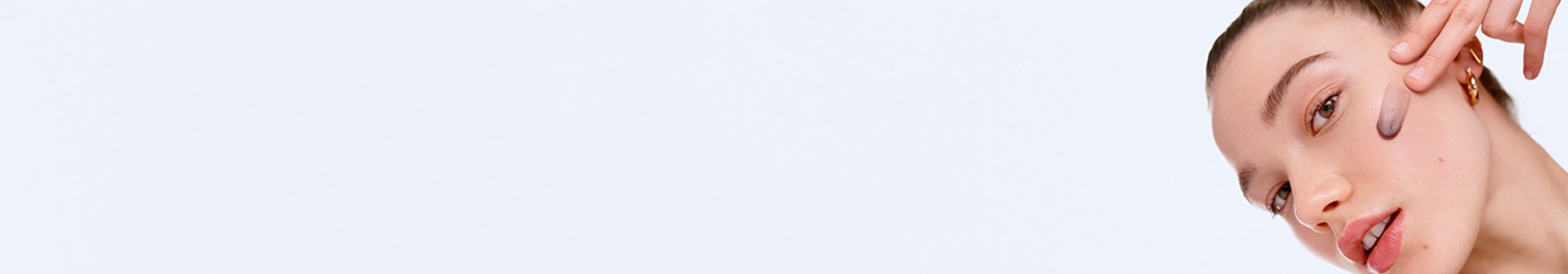 Eine junge Frau trägt ein Gesichts-Peeling auf ihre linke Wange auf