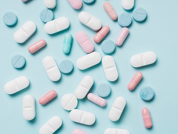 Verschiedene Tabletten in unterschiedlichen Farben auf einem blauen Grund