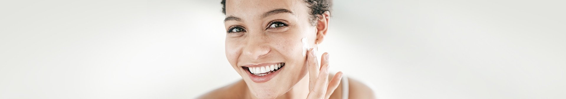 Lächelnde Frau trägt Creme auf