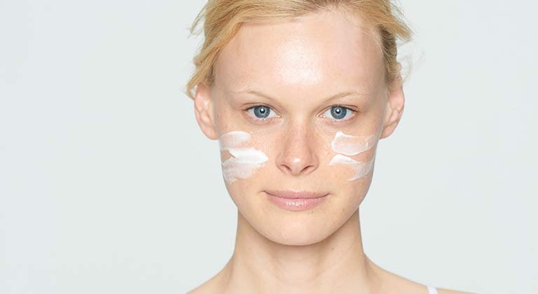 Frau mit Creme auf den Wangen