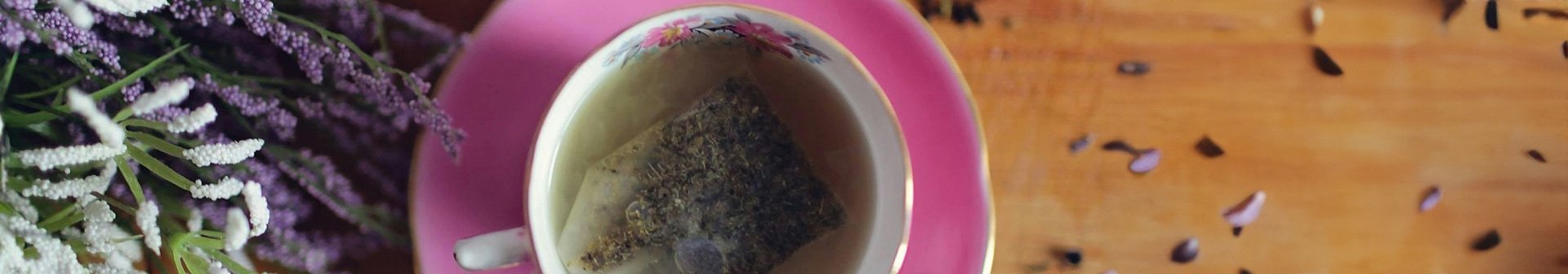 Tasse Tee neben der ein Strauß Lavendel liegt
