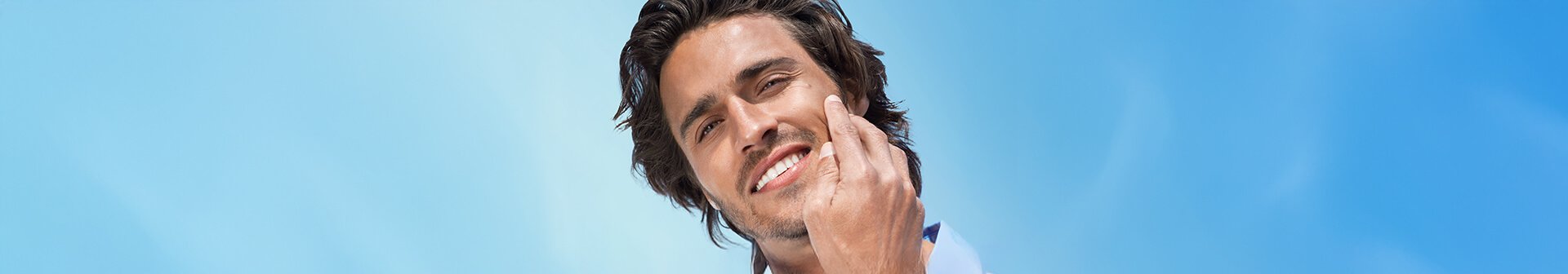 Lächelnder Mann streicht mit der Hand über seine Wange