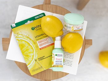 Holzhocker mit zwei Zitronen, einem Buch und drei Vitamin-C-Produkten von Garnier