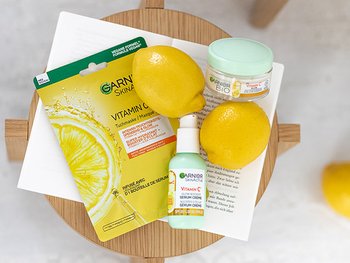Stillleben mit Vitamin C Tuchmaske, Serum & Glow Feuchtigkeitscreme sowie zwei Zitronen