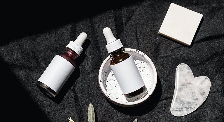 Stillleben mit zwei Ampullen, einem Olivenzweig und einer weißen Schale auf dunklem Untergrund