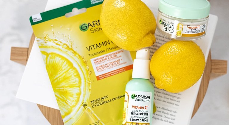 Stillleben auf einem kleinen Holztisch mit Zitronen, Vitamin C Serum Creme & Serum Maske