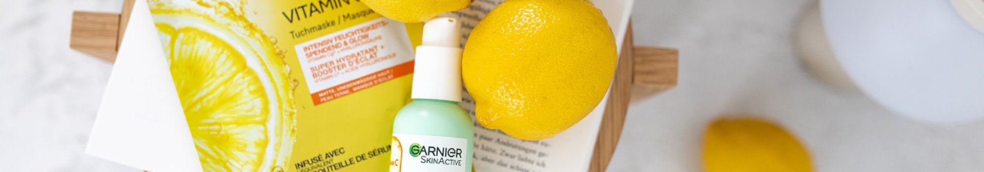 Stillleben auf einem kleinen Holztisch mit Zitronen, Vitamin C Serum Creme & Serum Maske