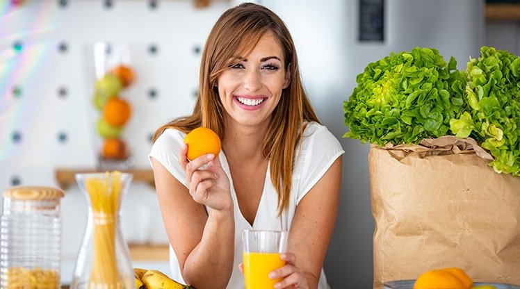 Eine lächelnde junge Frau mit einem Glas Orangensaft