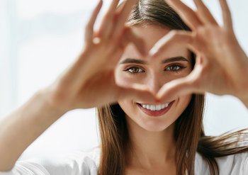 Eine junge Frau formt ein Herz mit ihren Fingern