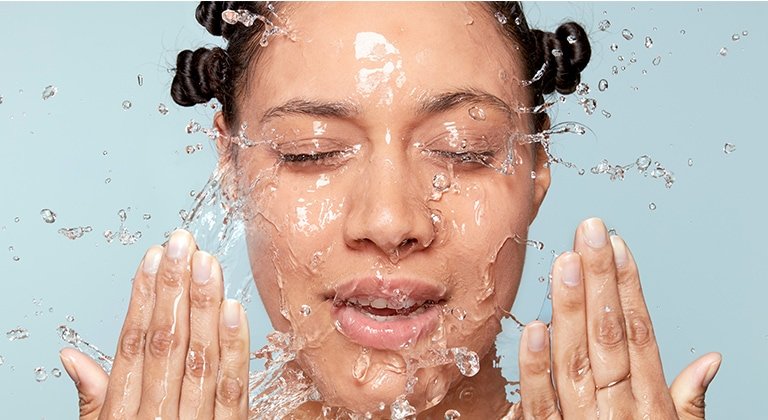 Frau wirft sich Wasser mit ihren Händen ins Gesicht