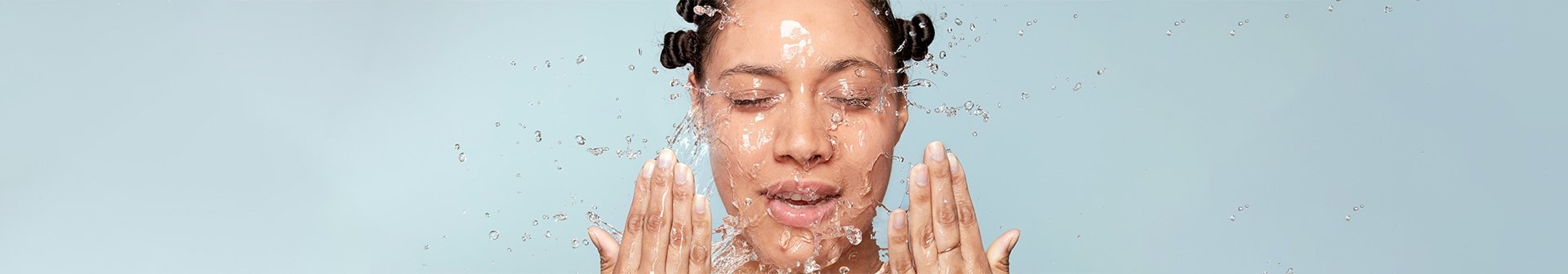 Frau wirft sich Wasser mit ihren Händen ins Gesicht
