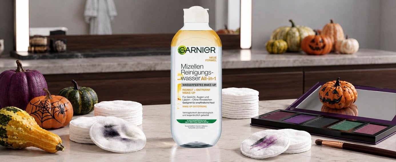 Das Garnier Mizellenwasser All-In-One Waterproof auf einem Schminktisch, umgeben von Make-Up Lidschattenpaletten, benutzten Abschminkpads und Halloween Dekoration.