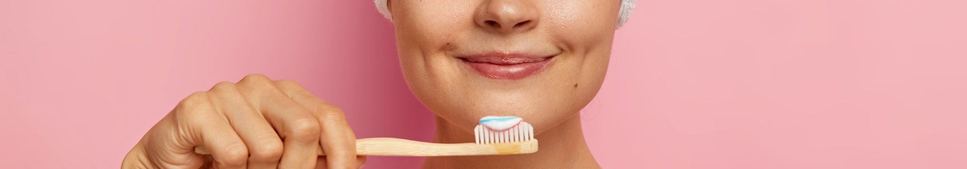 Eine junge Frau hält eine Zahnbürste mit Zahnpasta vor ihrem Gesicht 