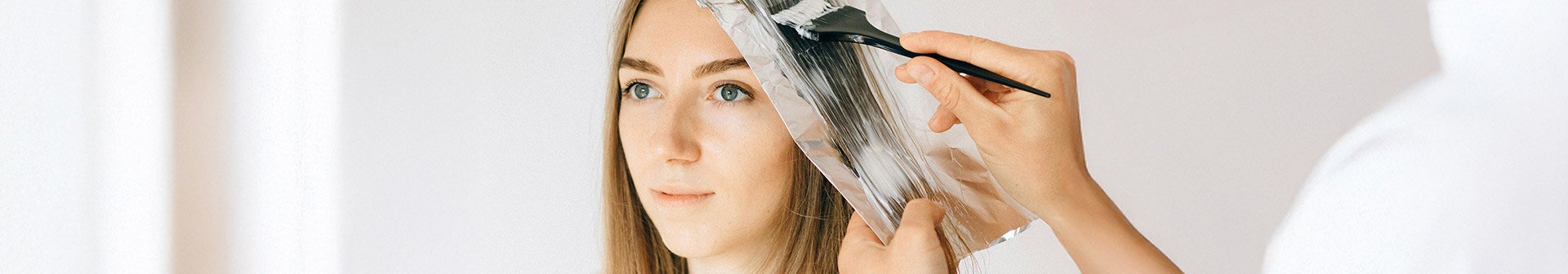 Dunkelblonde Frau, der die Haare gesträhnt werden