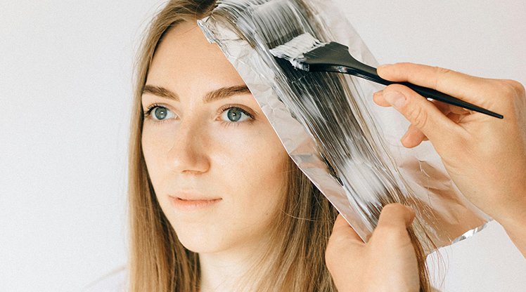 Dunkelblonde Frau, der die Haare gesträhnt werden